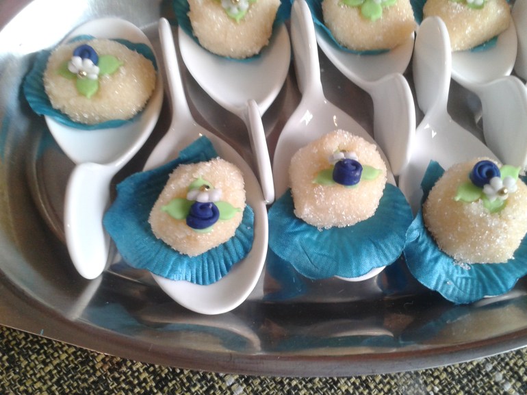 Doces colocados em colheres e forrados com pétalas  de rosa.